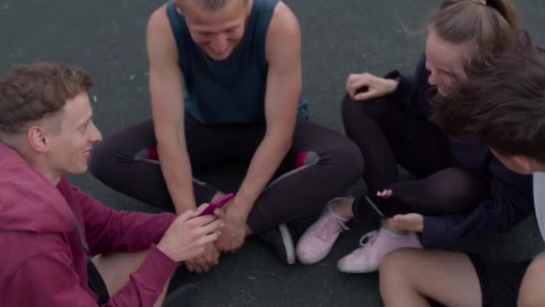 Друзья сидят на детской площадке — стоковое видео