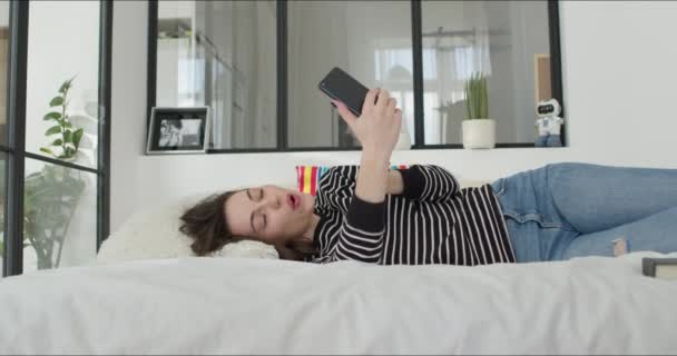Gadis berbaring di tempat tidur dan membuat foto — Stok Video
