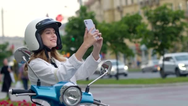 Senyum wanita keriting duduk di modern sepeda motor luar ruangan dan membuat selfie — Stok Video