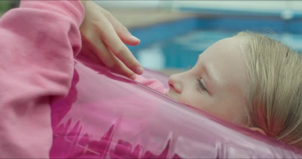 女孩躺在粉红色的大橡胶圈里 — 图库视频影像