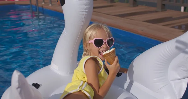 child swims on swan in blue pool