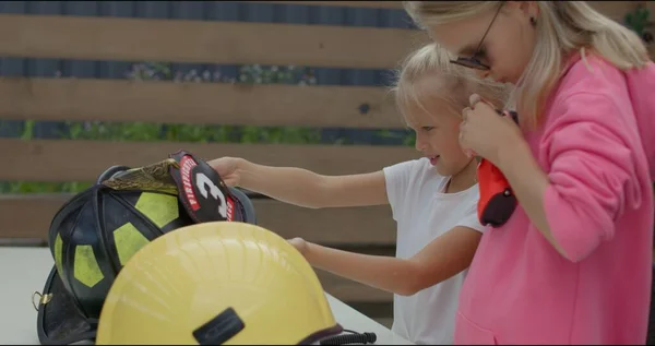 Twee meisjes zetten brandweerhelm op Rechtenvrije Stockfoto's