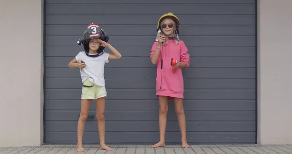 Two sisters in firefighter helmets — Stock Photo, Image