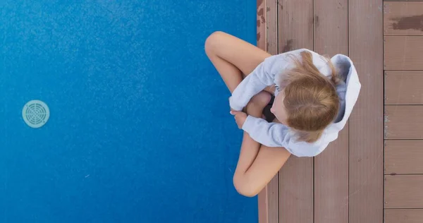 Niño solo se sienta en el borde de la piscina —  Fotos de Stock