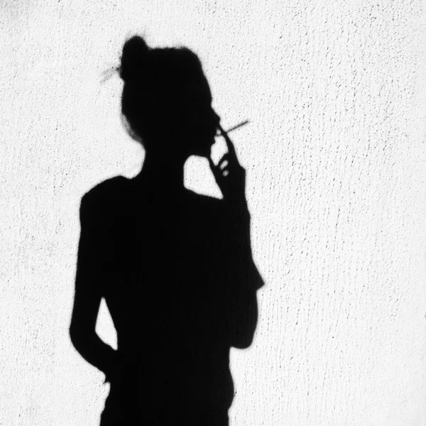 Shadow of girl smoking around on wall background — Stock Photo, Image