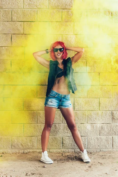 Joven chica sexy en peluca roja y chaqueta negra divirtiéndose en humo amarillo —  Fotos de Stock