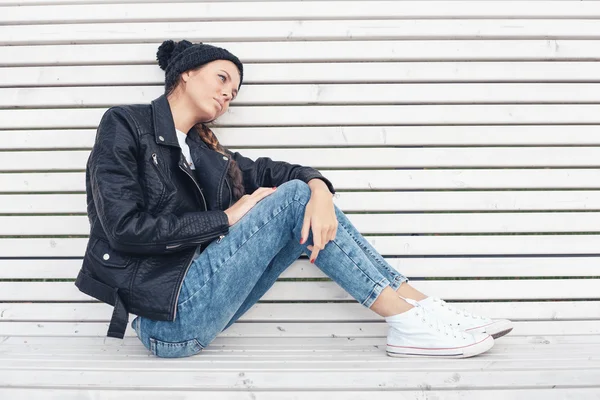 Schönes junges Mädchen sitzt auf einer weißen Bank im Park — Stockfoto