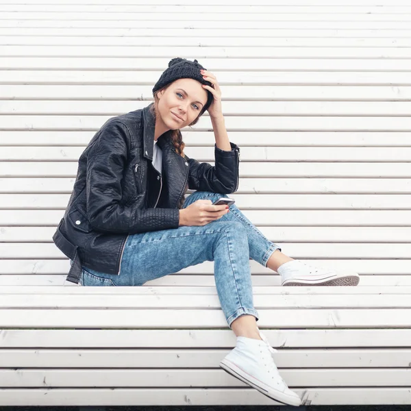 Beautiful young girl sitting on a white bench in the park — Stock Photo, Image