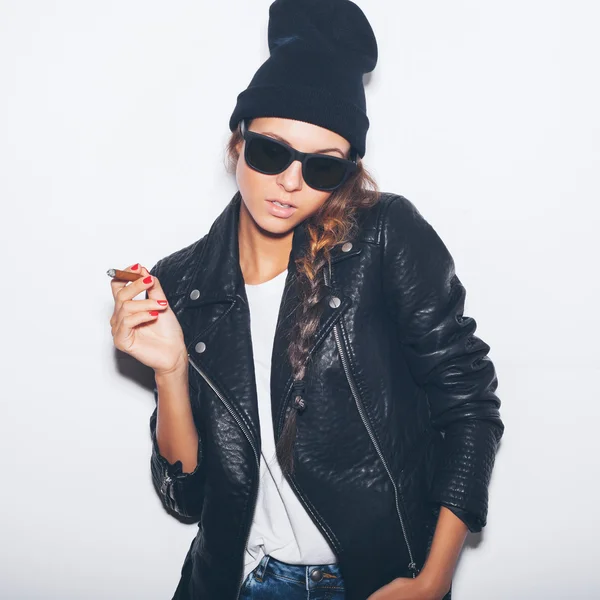 Hipster fille en lunettes de soleil et veste en cuir noir fumant cigare — Photo