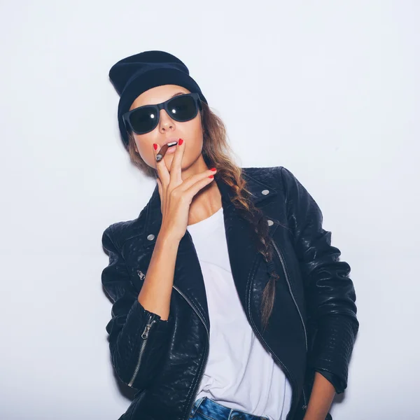 Hipster povýšený dívka v sluneční brýle a černou koženou bundu kouření doutníku — Stock fotografie