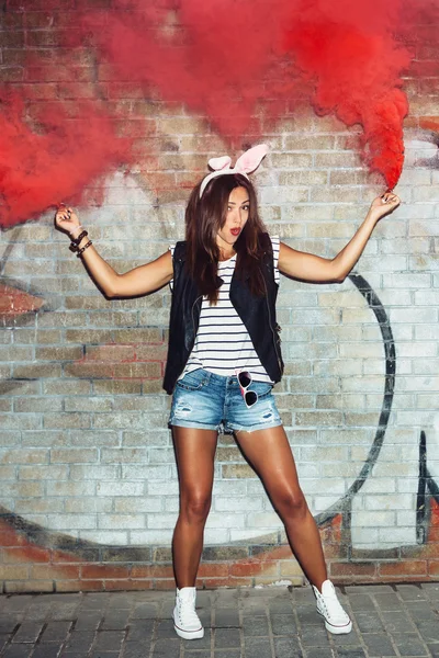 Naughty girl in pink rabbit ears with red smoke bombs — Stock Photo, Image