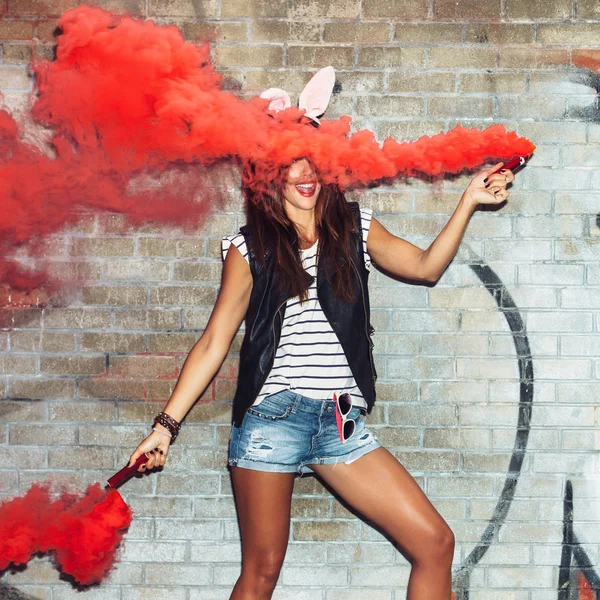 Naughty girl in pink rabbit ears with red smoke bombs — Stock Photo, Image