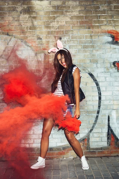 Femme sexy dans les oreilles de lapin agitant des bombes fumigènes rouges — Photo