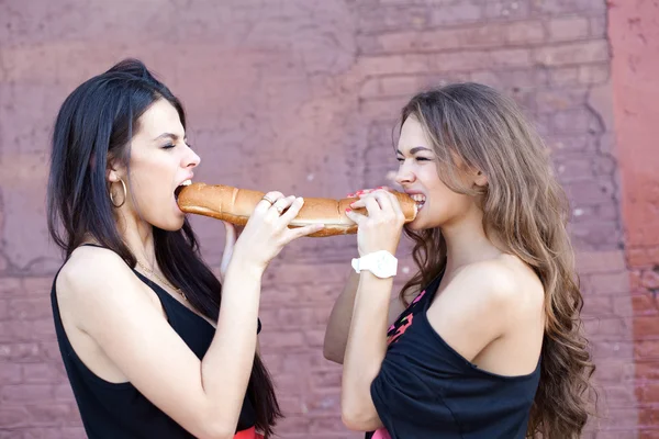 Two young women eating bread. — Zdjęcie stockowe