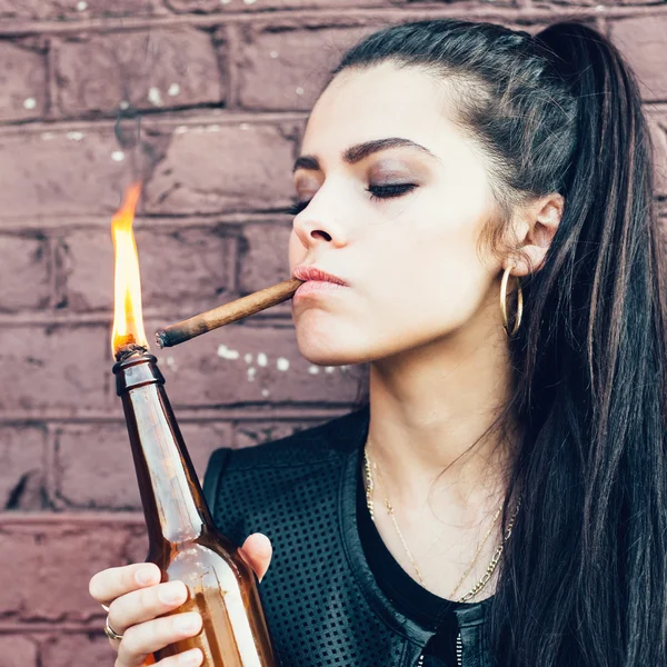 Плохая брюнетка закуривает сигарету из коктейльной бомбы Молотова в руке — стоковое фото