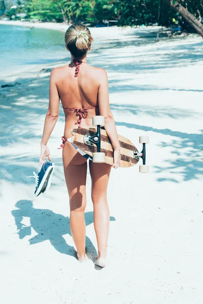 Ung kvinna med longboard i hand gå på vit sand — Stockfoto