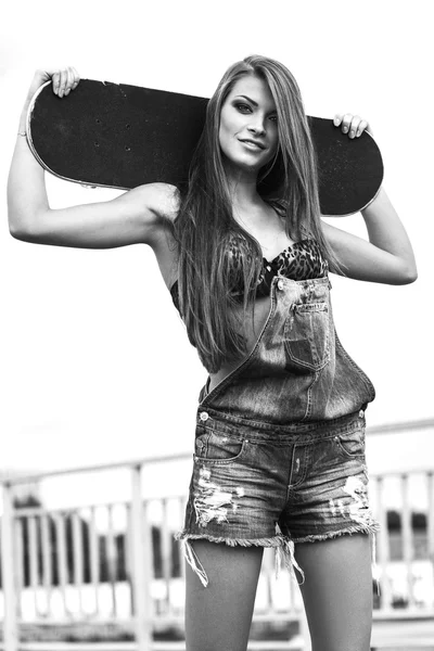 Jovem bonita andando e segurando um skate — Fotografia de Stock