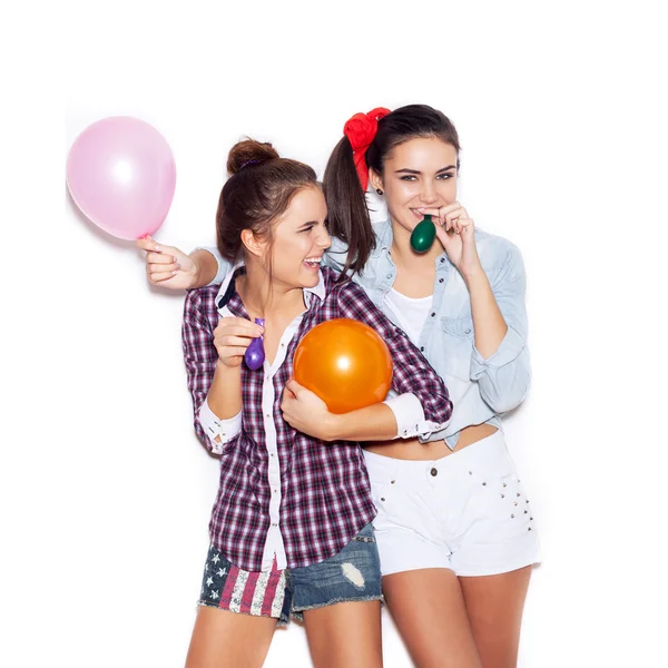 Две счастливые девушки веселятся с цветными воздушными шарами — стоковое фото