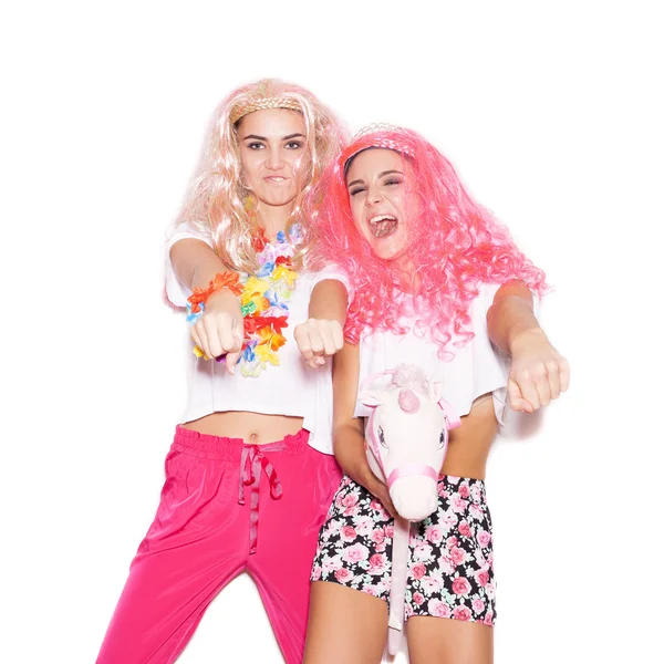 Two girlfriends in colorful wigs and clothing have fun with  unicorn — Stock Photo, Image
