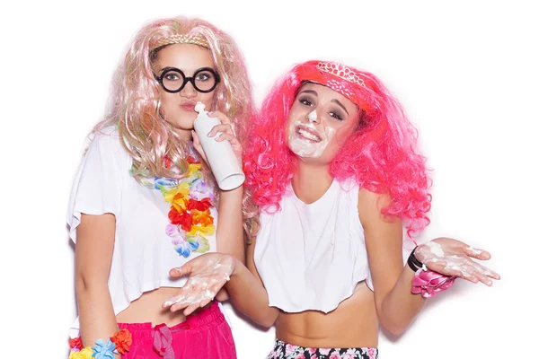 Funny girls in colored wigs and glasses stained with cream — Stock Photo, Image