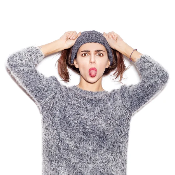Funky dívka v pletený svetr a klobouk ukazující jazyk — Stock fotografie