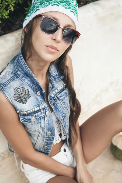Женщина в солнцезащитных очках и джинсовом жилете смотрит в камеру — стоковое фото