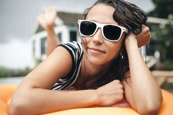 Young woman in bikini  lying on an inflatable mattress near the pool — Stock Photo, Image