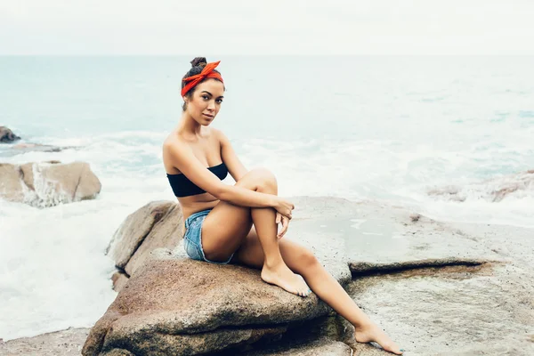 Girl sitting on the rocks on the shore of the sea — Stock Photo, Image