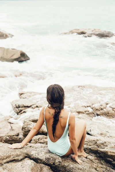 Female model wearing bikini posing on a rock with waves — Stock Photo, Image
