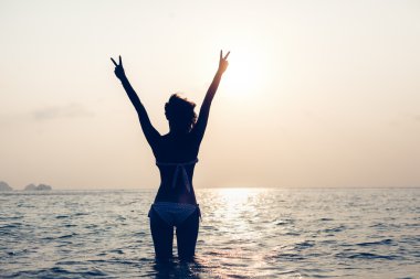 Woman enjoying freedom feeling happy at beach at sunset clipart