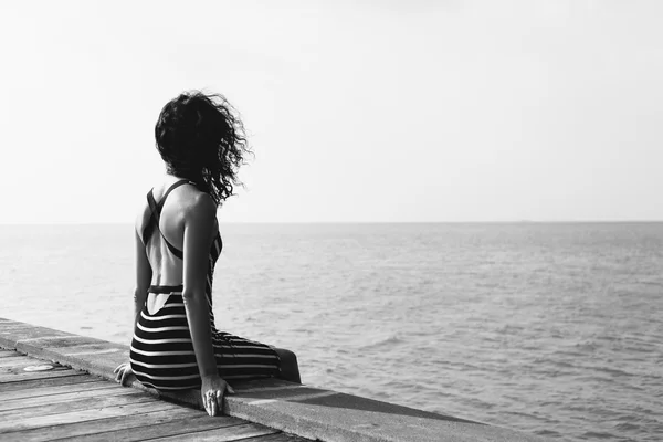 桟橋に一人で座っている若いきれいな女性 — ストック写真