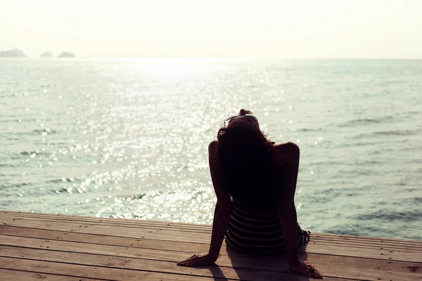 Young pretty woman sitting alone on the pier — Stock Photo, Image