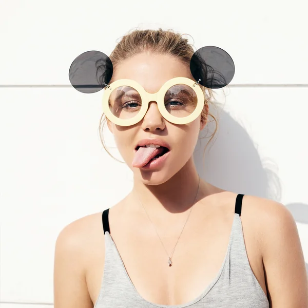Молодая девушка в солнечных очках показывает язык — стоковое фото
