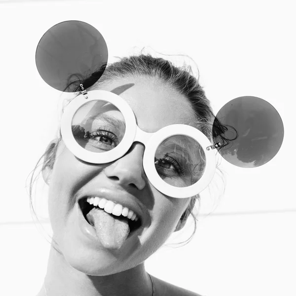 Молода дівчина в сонцезахисних окулярах показує язик — стокове фото