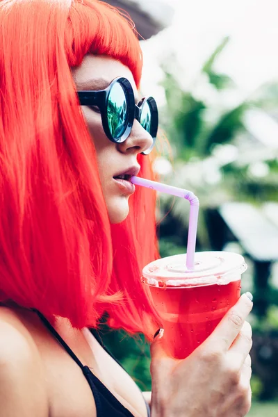 Frau mit roter Perücke und schwarzem Bikini trinkt Cocktail — Stockfoto