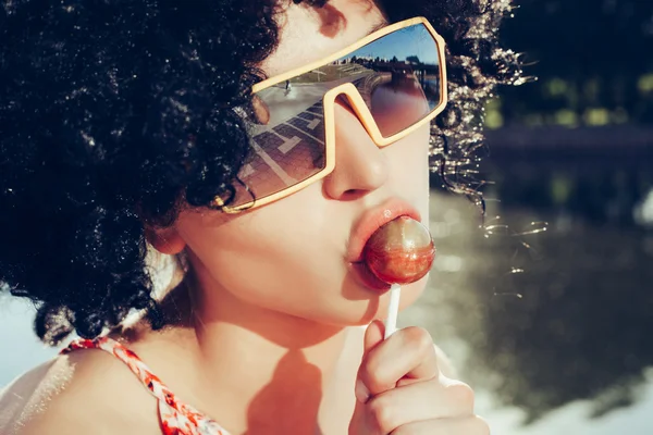 Sexig tjej med svart peruk hår suger lollipop — Stockfoto
