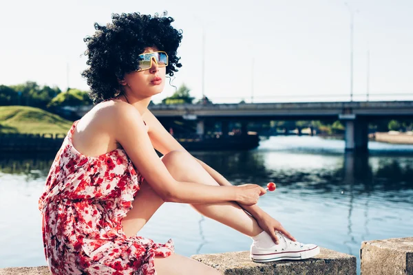 Sexy meisje met zwarte pruik haar zuigt lolly — Stockfoto