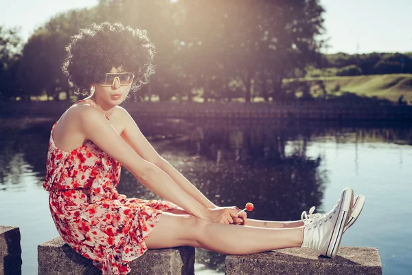 Sexy meisje met zwarte pruik haar zuigt lolly — Stockfoto