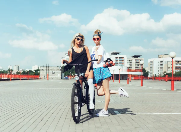 Fashion portrait of attractive young girls with bicycle — Stock Photo, Image