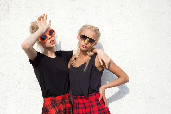 Two pretty hipster sisters against urban white wall — Stock Photo, Image