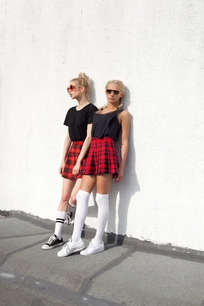Две симпатичные хипстерские сестры на фоне городской белой стены — стоковое фото