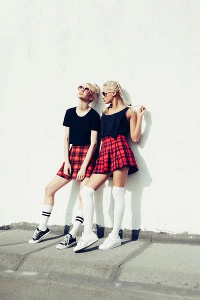 Zwei hübsche Hipster-Schwestern gegen urbane weiße Wand — Stockfoto