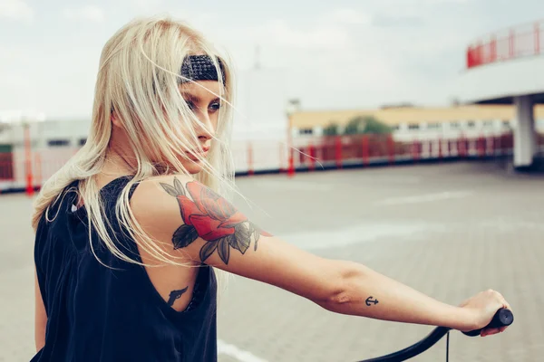 Pretty blonde woman with bike in city — Stock Photo, Image