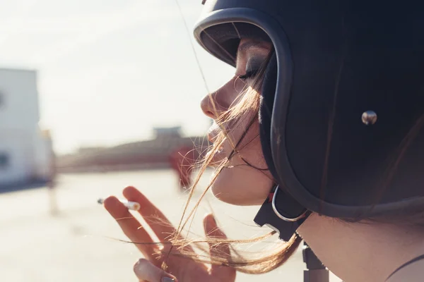 Mooie vrouw in motorfiets helm roken sigaretten — Stockfoto