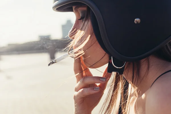 Mooie vrouw in motorfiets helm roken sigaretten — Stockfoto