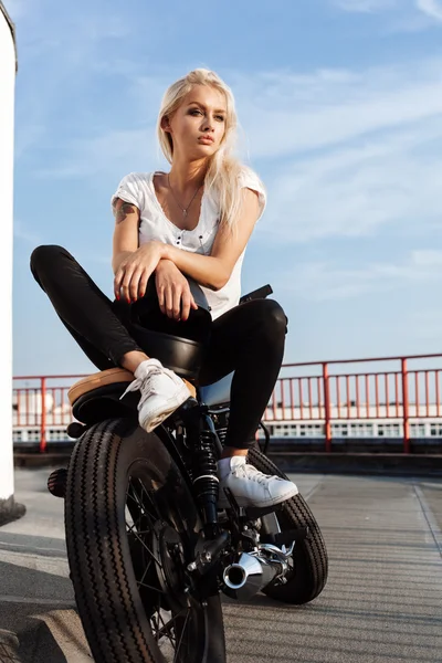 Biker girl on motorcycle looking at the sunset — Stock Photo, Image