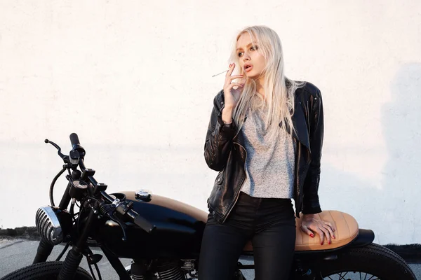 Mujer sentada en motocicleta vintage y fumando sigarette —  Fotos de Stock