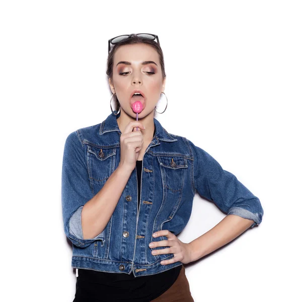 Fashion Girl wearing blue jeans jacket licking candy — Stock Photo, Image