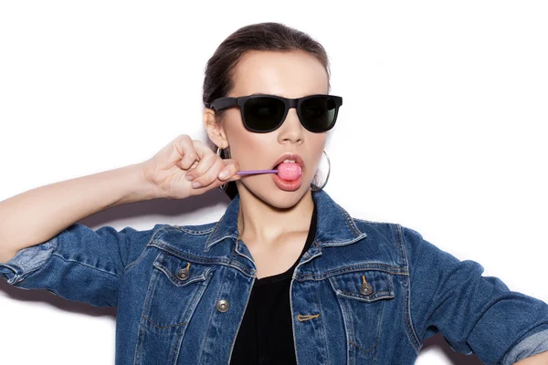 Fashion Girl wearing blue jeans jacket licking candy — Stock Photo, Image