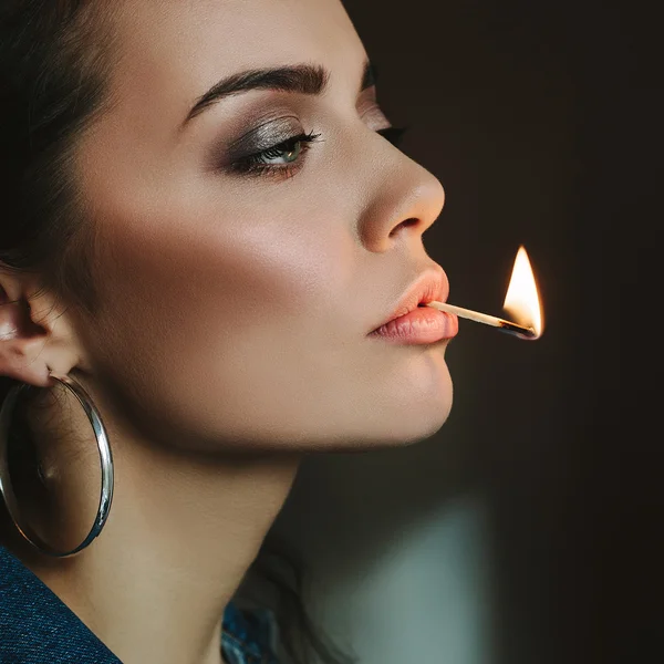 Woman with perfect skin holding her lips with a match flame — Stock Photo, Image